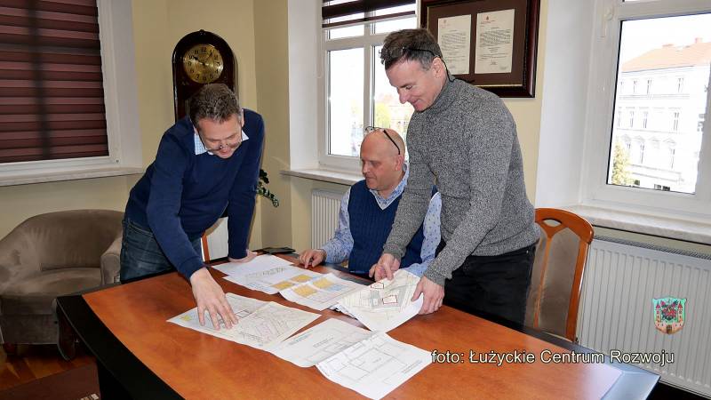 trzech mężczyzn przegląda dokumenty rozłożone na stole
